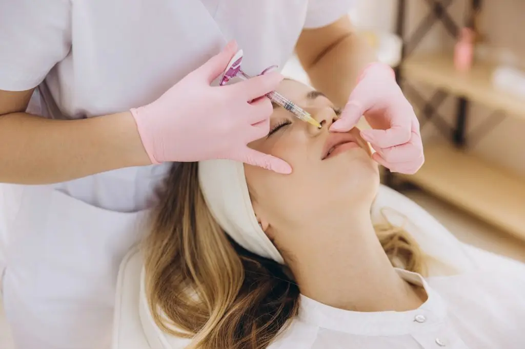 Cosmetic professional administering dermal lip filler, performing precision injection treatment