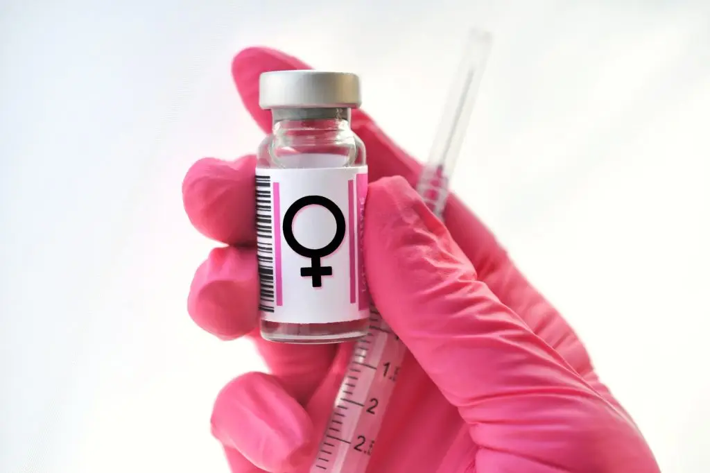 Pink gloved hand holding a vial with female symbol, hormones injections, concept hormone replacement