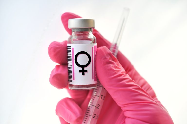 Pink gloved hand holding a vial with female symbol, hormones injections, concept hormone replacement