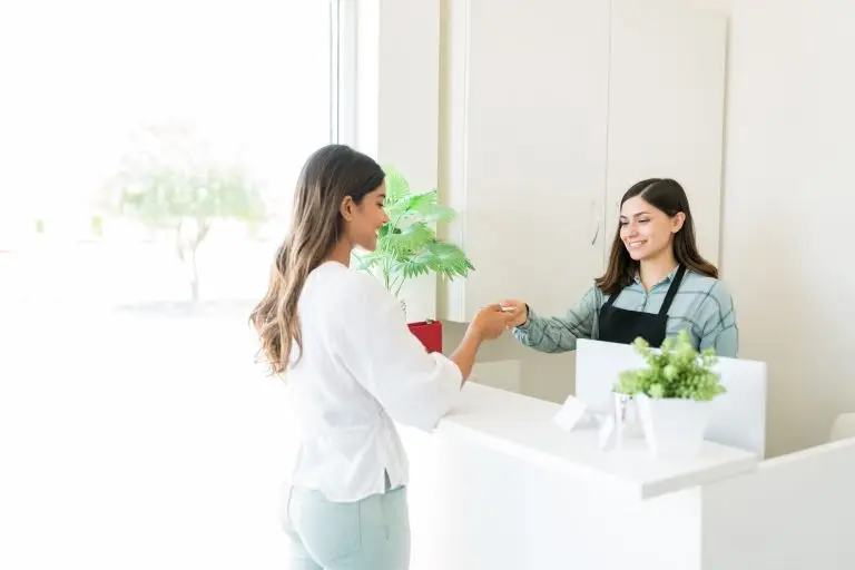 Satisfied Client Paying At Reception Desk In Spa