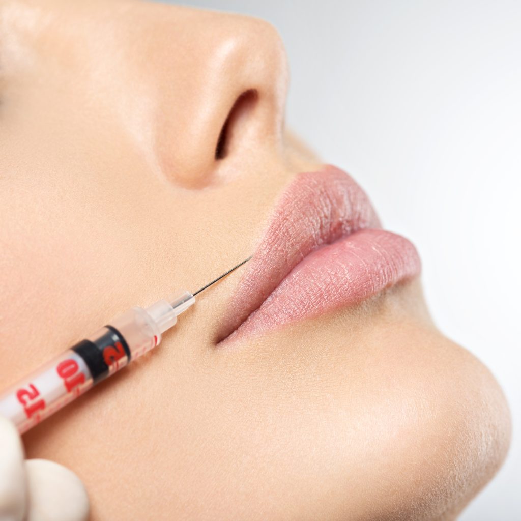 young woman gets botox injection in her lips