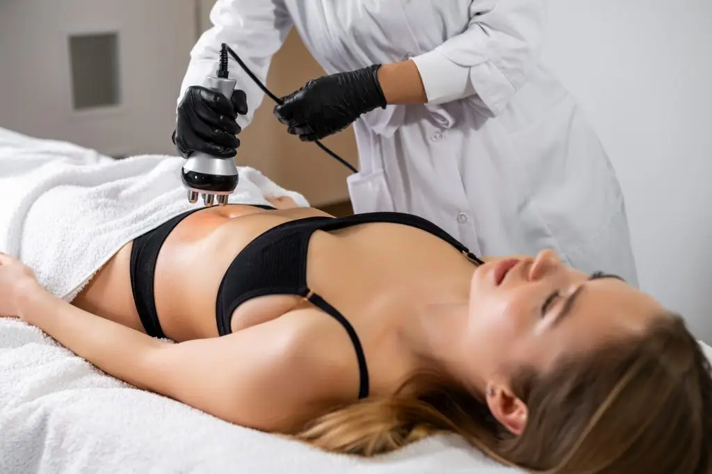Young woman is lying while getting RF lifting of the body in a spa beauty salon.